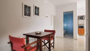 A dining area with a wooden table and chairs, a small bowl, and two framed artworks on the wall. - Central sunset view #1 (Himarë)