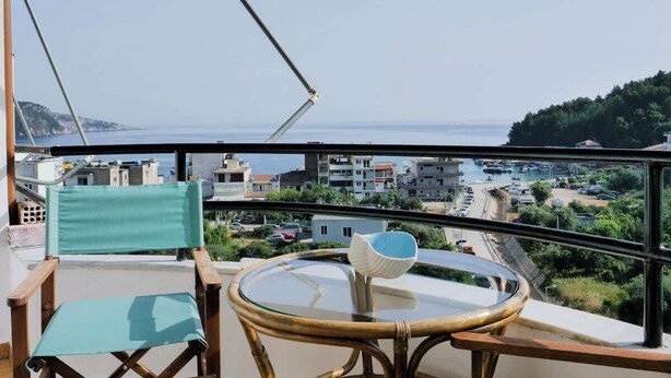 A balcony with a view of the sea, a table with a glass top, and two chairs. - Central sunset view #1 (Himarë)