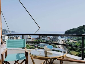 A balcony with a view of the sea, a table with a glass top, and two chairs. - Central sunset view #1 (Himarë)