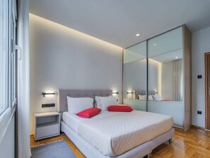A modern bedroom with a bed, nightstands, a large mirror, and a wooden floor. - Danae's newly renovated entire cozy apartment (Athina)