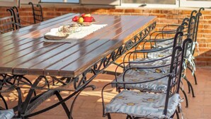 A wooden table with metal chairs, a tiled floor, and a view of the sea through large windows. - Ionian Manor Estate villa (Porto Palermo)