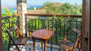 A balcony with a table and two chairs, overlooking a hillside with greenery and a distant view of the sea. - Ionian Manor Estate villa (Porto Palermo)