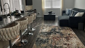 Ein modernes Wohnzimmer mit Bar, einer Couch und einem großen Fenster mit Jalousien.