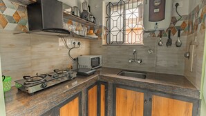 Cocina con estufa a gas, microondas, pileta y ventana con reja de metal.