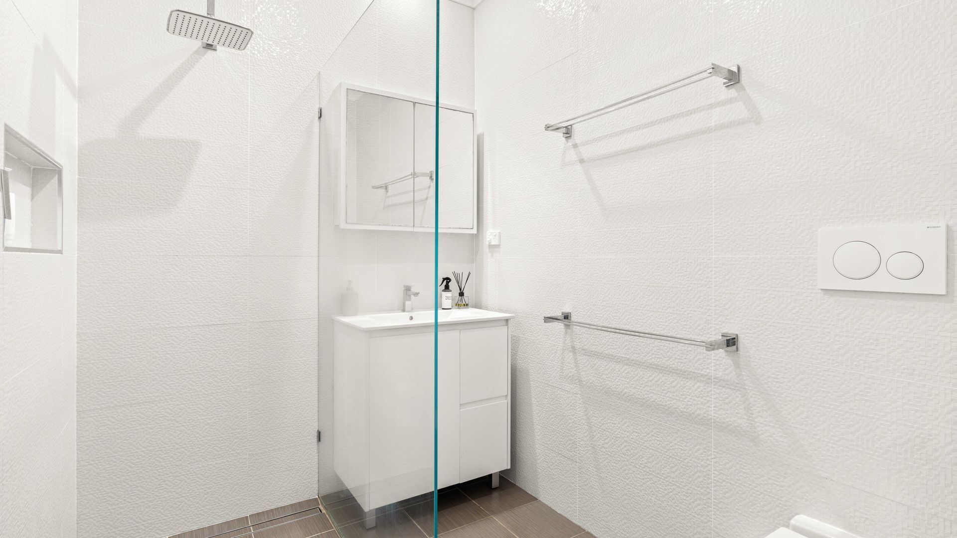 Une salle de bain moderne avec une douche à parois de verre, un lavabo blanc et un porte-serviettes.