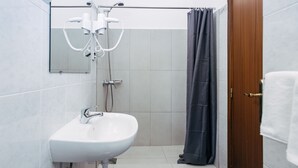A bathroom with a white sink, a shower with a dark curtain, and a wooden door. - Economy Studio Apartment in the heart of Funchal. 2' walk from Cathedral. (Funchal)