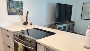 Eine moderne Küche mit Einbauofen, Kochfeld und Mikrowelle. Über einem Schrank befindet sich ein Fernseher.