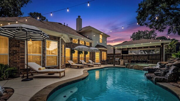 Un jardin avec une piscine, des chaises longues et un patio couvert.