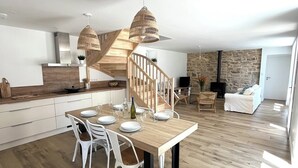 Una cocina amplia con una isla central, piso de madera y una escalera moderna.
