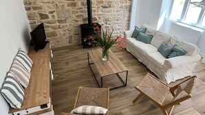 Una sala de estar con pared de piedra, chimenea, sofá, mesa de centro y una silla.