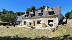 Una casa de piedra con un patio, mobiliario exterior y una escalera que conduce a la entrada.