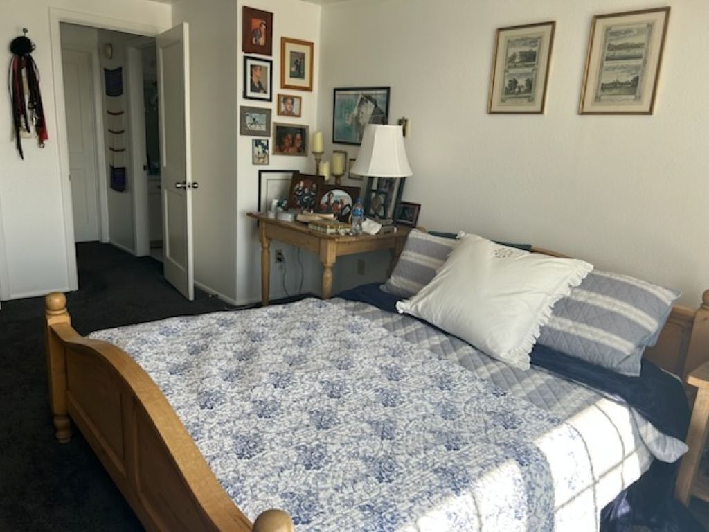 Un dormitorio con cama, mesita de noche, lámpara y adornos en la pared.