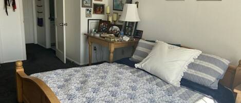Un dormitorio con cama, mesita de noche, lámpara y adornos en la pared.