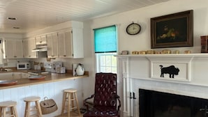 A kitchen with white cabinets, a wooden countertop, a red upholstered chair, and a fireplace.