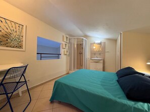 Une chambre à coucher comprenant un lit, un bureau, une chaise, une douche et une salle de bain.