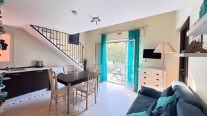 Een kleine woonruimte met een eethoek, kitchenette en een slaapbank.
