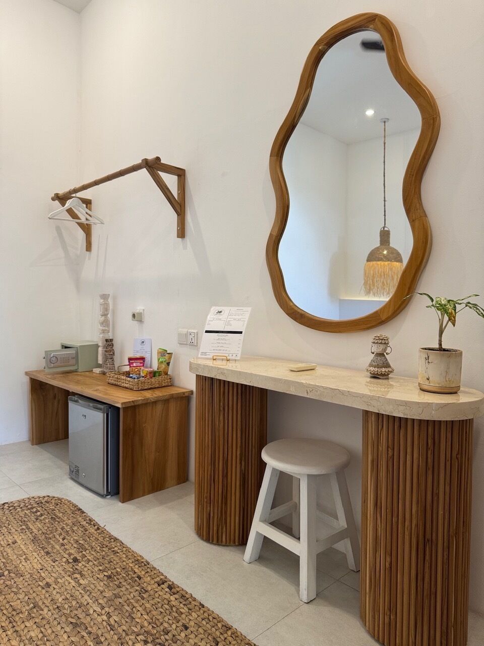 Casa de banho com toucador de madeira, espelho, banqueta e uma pequena planta em vaso.