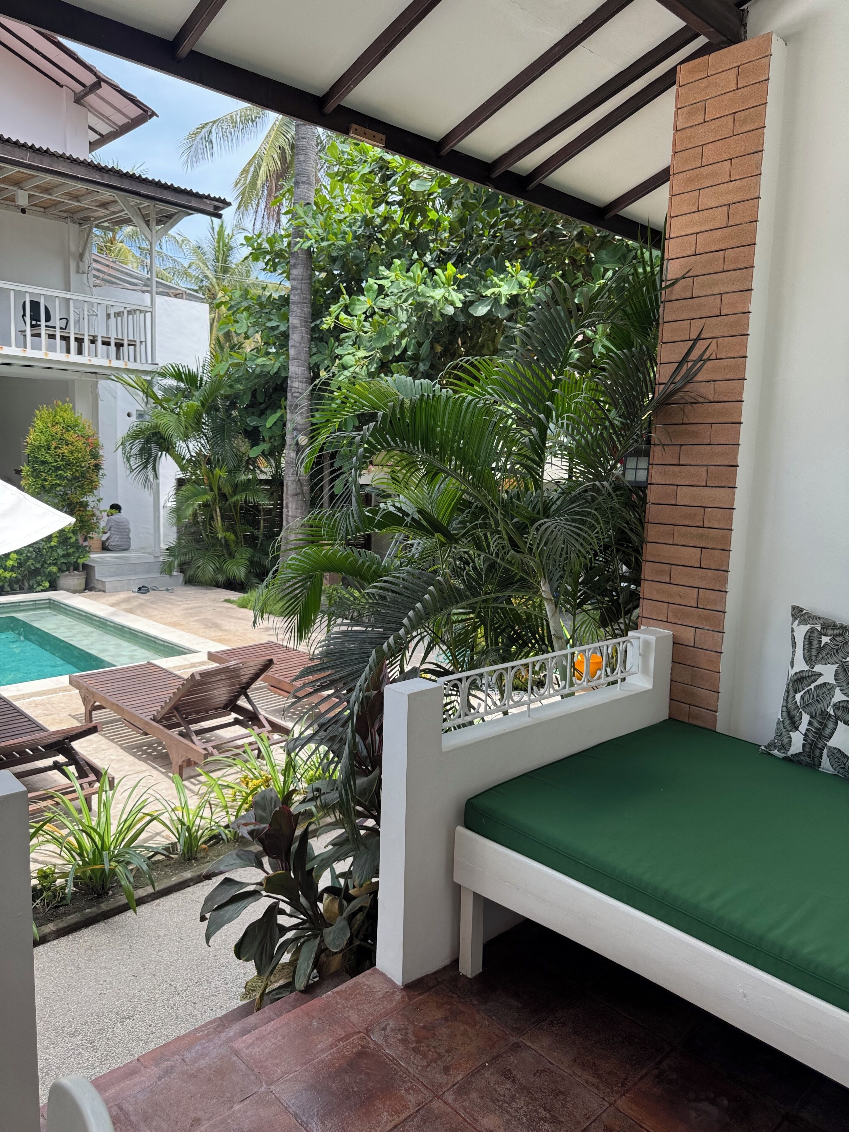 Un balcon avec un lit, une piscine et une végétation luxuriante.