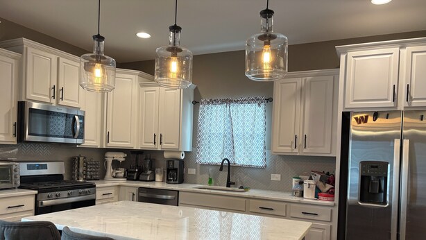 A modern kitchen with white cabinets, stainless steel appliances, a marble island, and tufted chairs. - Delightful 4-bedroom house with AC in charming High Point (High Point)