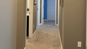 A hallway with carpeted floors, a white door, and a blue door. - Delightful 4-bedroom house with AC in charming High Point (High Point)