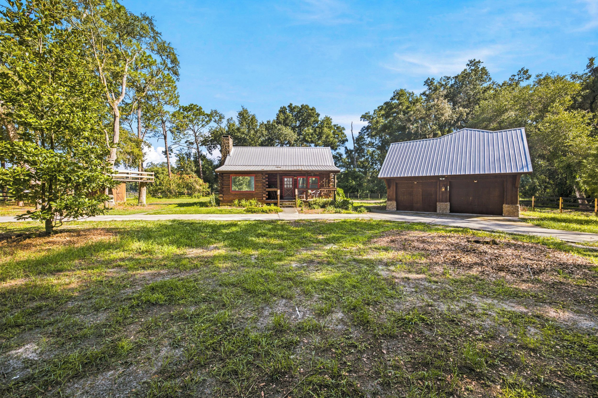 A rustic cabin with a metal roof, surrounded by a well-maintained lawn and trees.