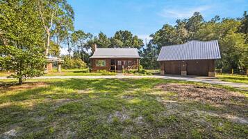 A rustic cabin with a metal roof, surrounded by a well-maintained lawn and trees.