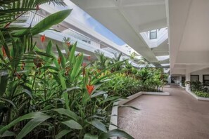 A modern indoor space with a central pathway, surrounded by lush greenery and a high ceiling with skylights. - Fabulous 2-bedroom 2-bath in Royal Sea Cliff Resort in sunny Kailua-Kona (Kailua-Kona)