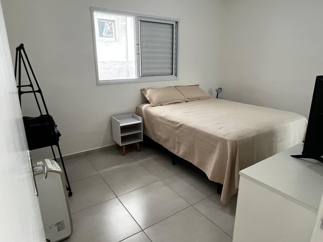 Quarto com cama, janela, escrivaninha e cadeira.