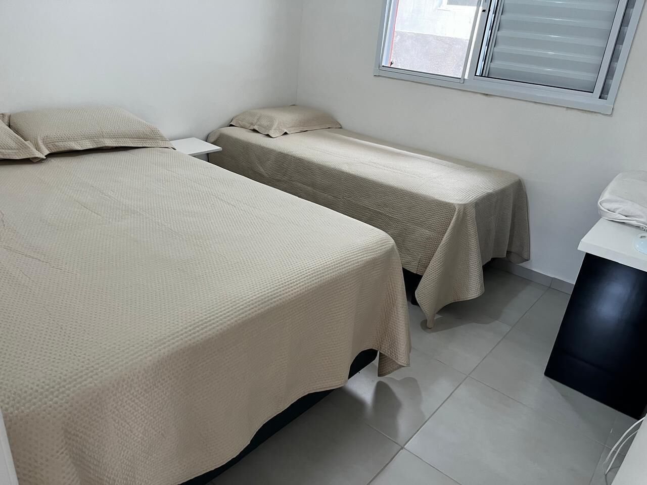 A room with two beds, a small table, and a window.