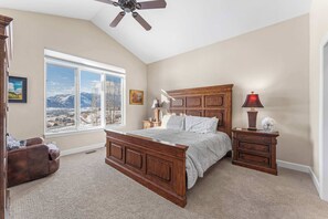 A bedroom with a large window, a bed, a nightstand, a dresser, and a ceiling fan. - Mtn House Movie Room HOA Pool,Hot Tub, great Views (Eden)