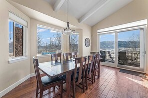 A dining room with a wooden table and chairs, large windows, a chandelier, and a view of mountains. - Mtn House Movie Room HOA Pool,Hot Tub, great Views (Eden)