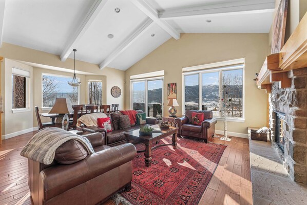 A spacious living room with a fireplace, large windows, and a high ceiling. - Mtn House Movie Room HOA Pool,Hot Tub, great Views (Eden)
