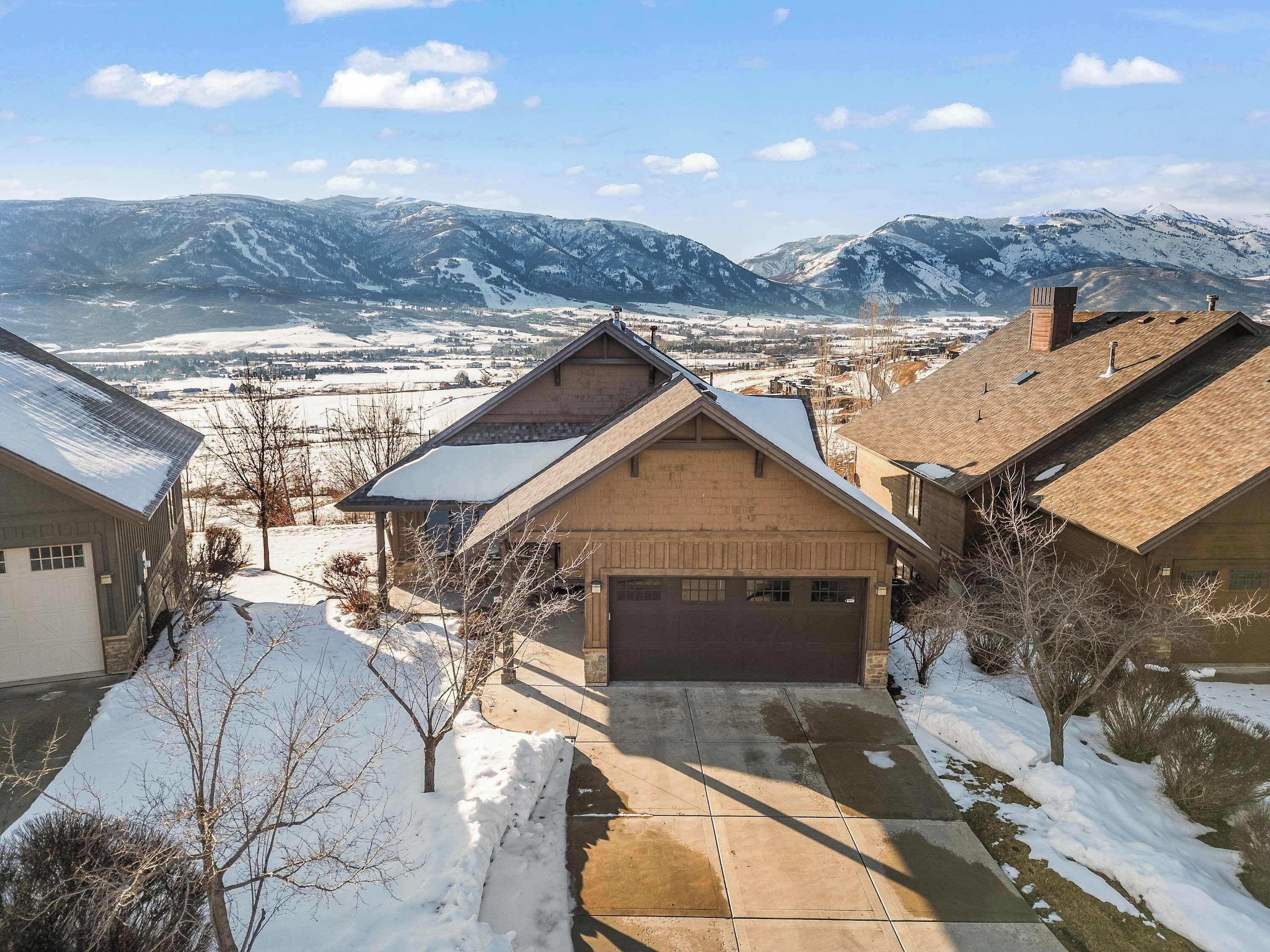 A residential area with houses, a driveway, and a mountain backdrop.