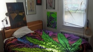 A bedroom with a bed, a desk, a chair, a window with blinds, and artwork on the walls. - Spacious 4-bedroom estate in adorable Carmel Hamlet with AC (Carmel Hamlet)