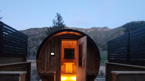 A wooden structure with an open entrance, a bench on either side, and a view of a mountainous landscape.