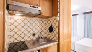 Une petite cuisine équipée comprenant une cuisinière, un évier et un crédence décorée.