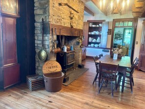 A rustic interior with a stone fireplace, wooden dining table, and vintage kitchenware.