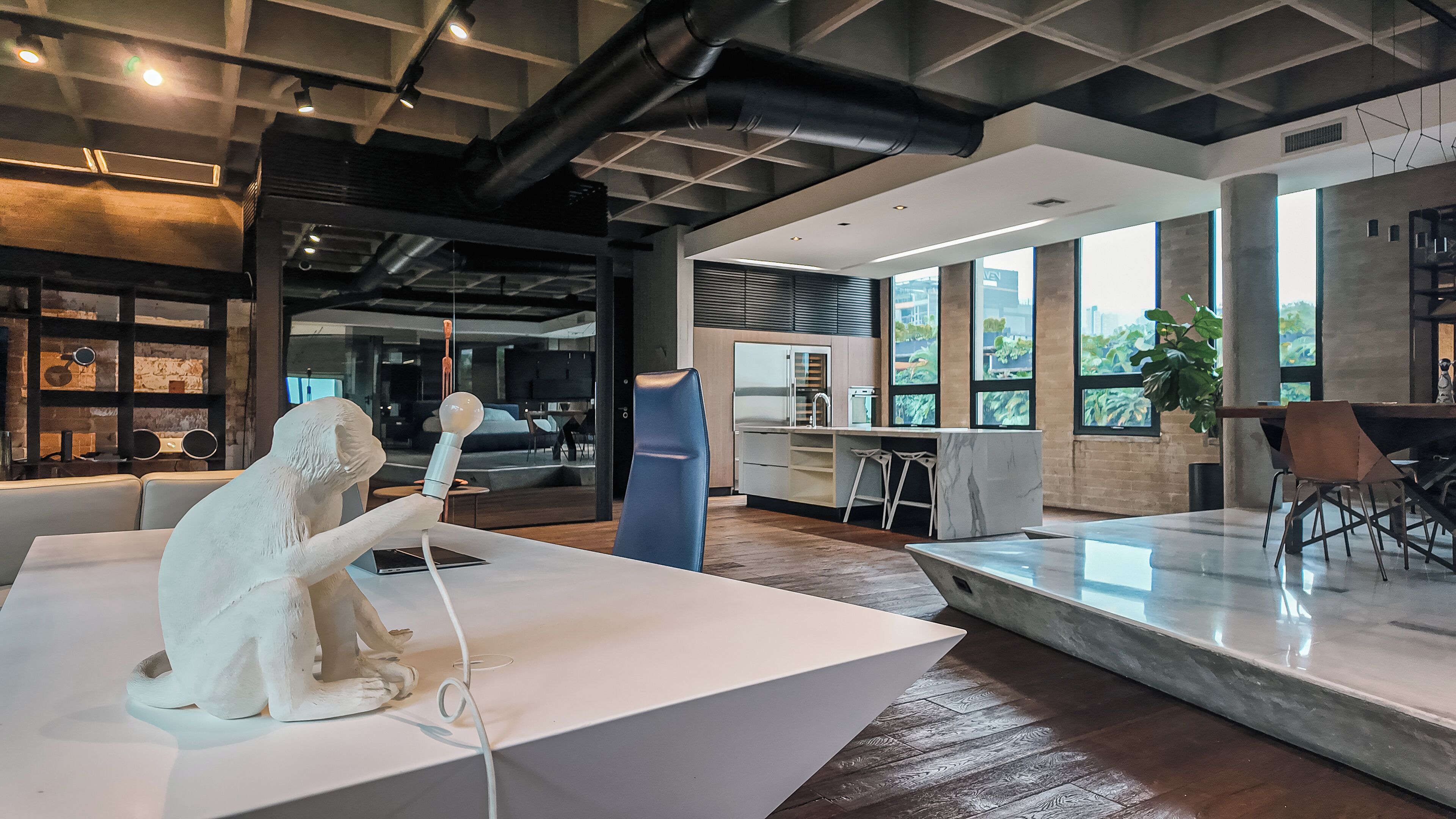 Ein modernes Interieur mit einer weißen Skulptur, einer Küchenzeile und großen Fenstern mit Blick.