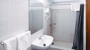 Ein Badezimmer mit Waschbecken, Spiegel, Dusche und Handtuchhalter.