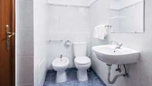 Ein Badezimmer mit Toilette, Bidet und Waschbecken, alles in Weiß, mit blau gefliestem Boden.