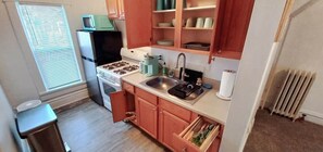 A compact kitchen with a stove, sink, and cabinets. - Earthvine: Cozy Zen Retreat Pets-OK Downtown-ISU (Ames)