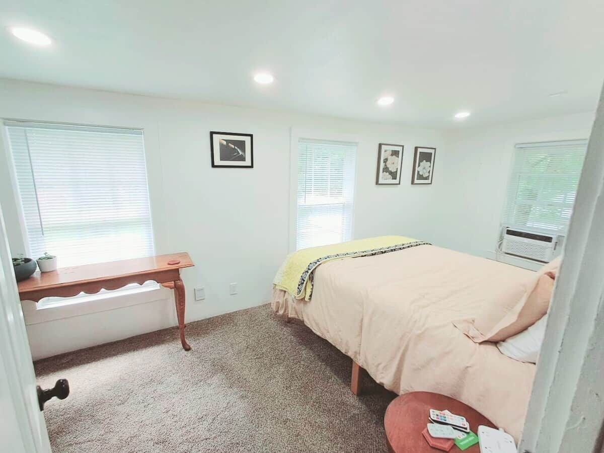 A bedroom with a bed, a desk, a chair, a radiator, and a window.