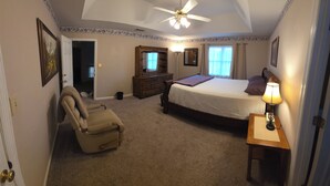 A bedroom with a bed, a chair, a dresser, a lamp, and a ceiling fan. - Beautiful 4BR/3BA Fully Furnished Home in Quiet Neighborhood (Evans)