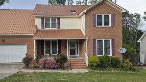 A two-story house with a garage, a front porch, and a satellite dish. - Beautiful 4BR/3BA Fully Furnished Home in Quiet Neighborhood (Evans)