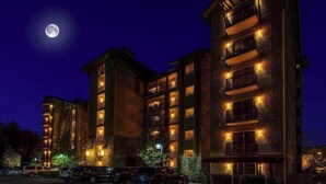 Un hôtel à plusieurs étages doté de balcons, d’un parking et où l’on peut admirer la lune dans le ciel.