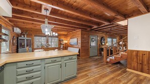 A wooden cabin interior with a kitchen, dining area, and staircase. - Maggie Valley Cabin w/ Hot Tub, Fire Pit, Game Room, Sleeps 8, Trailer Friendly (Maggie Valley)