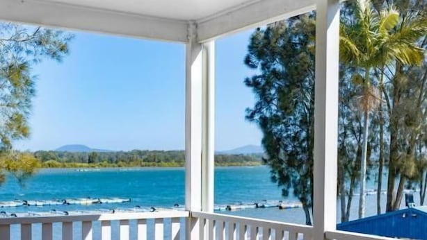 Un'area esterna coperta con vista sul mare, una sedia e un pontile in legno.