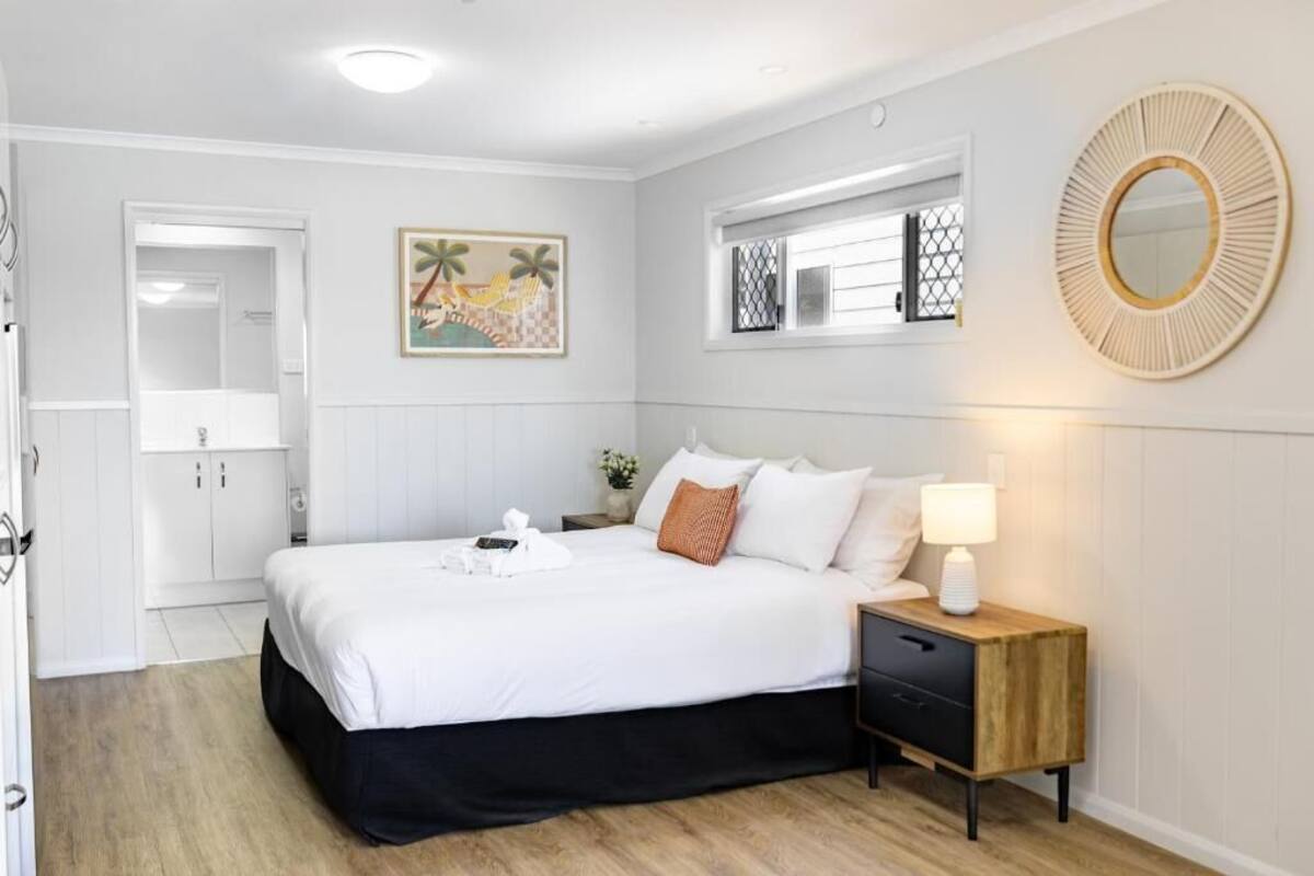 A bedroom with a bed, bedside table, and a window with a view.