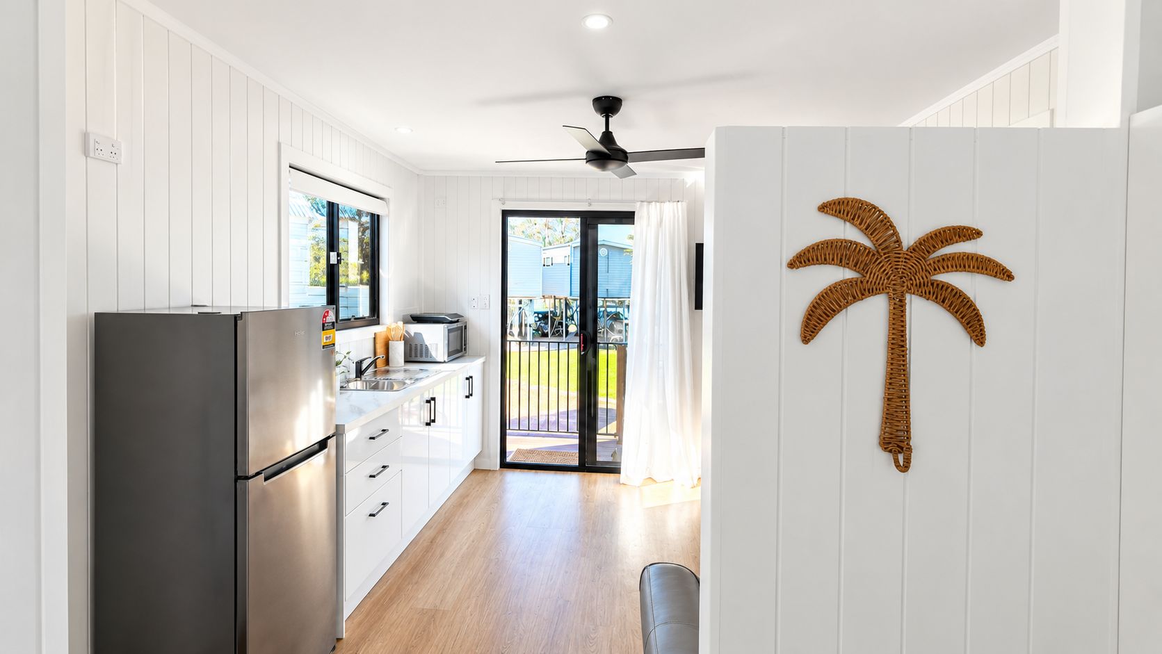 A modern kitchen with a stainless steel refrigerator, white cabinetry, and a large window.