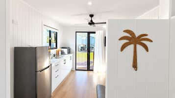 A modern kitchen with a stainless steel refrigerator, white cabinetry, and a large window.